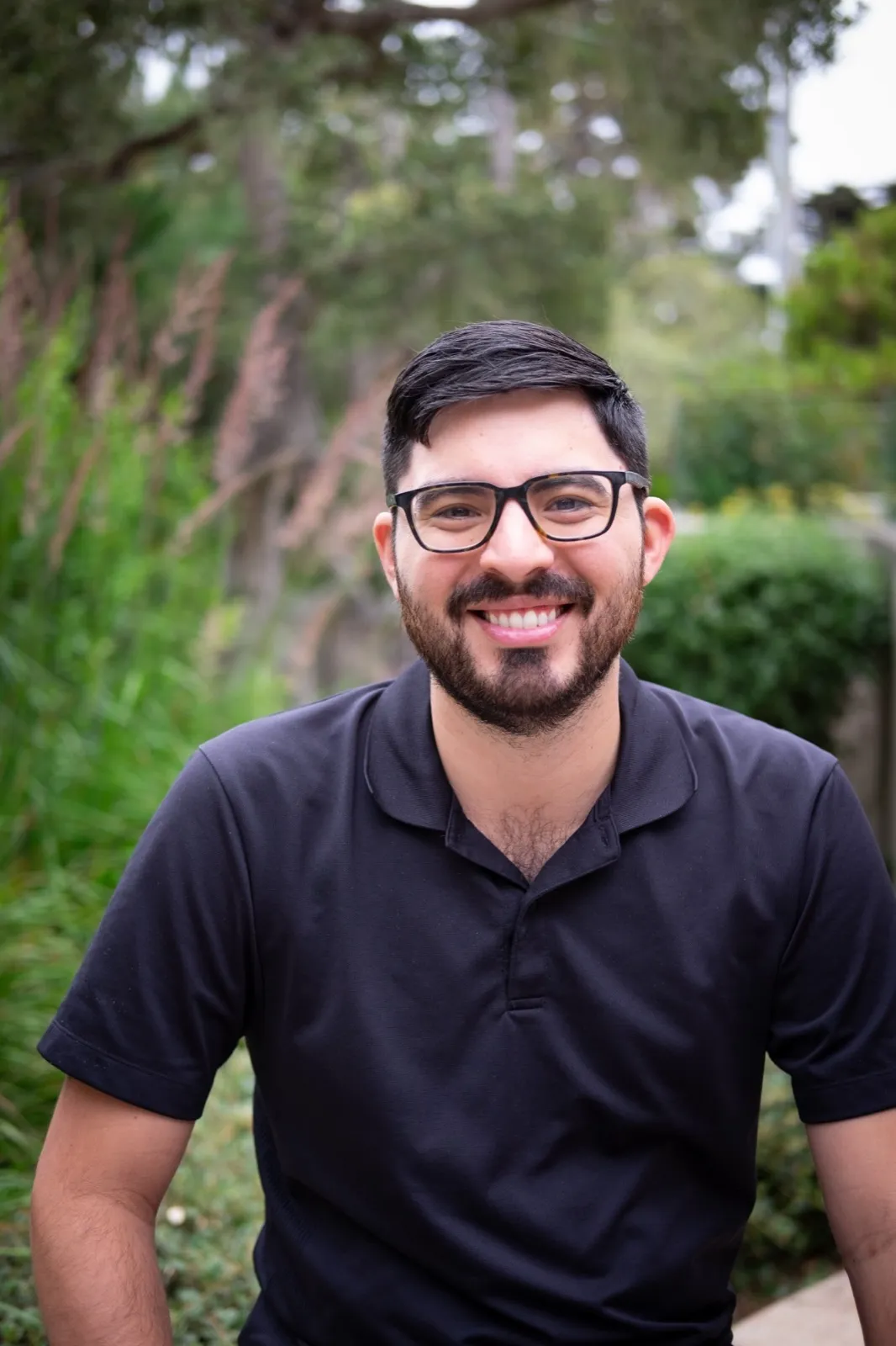 Aaron Rosales, smiling, outdoors among green plants
